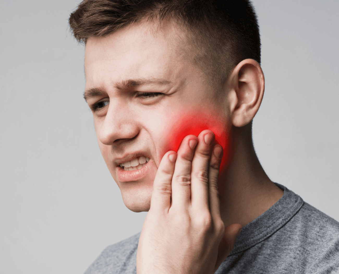 Man experiencing dental pain holding his jaw
