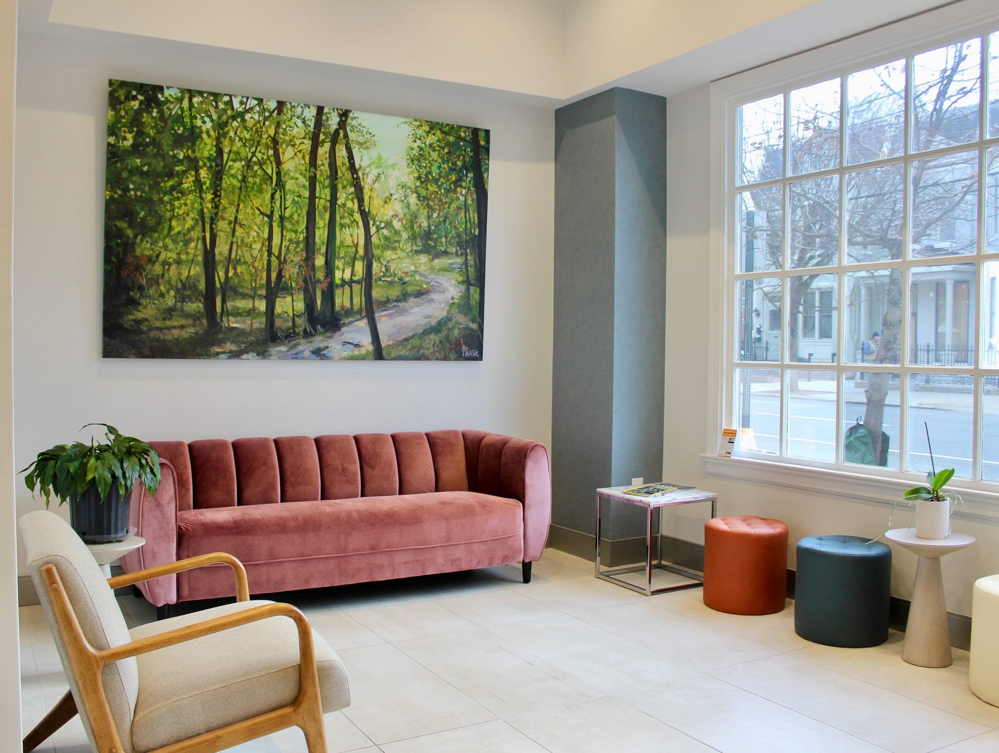Our welcoming waiting room with pink velvet sofa, local landscape painting, and large windows