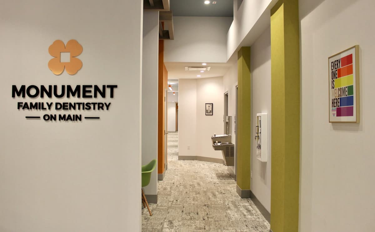 Monument Family Dentistry hallway with the Everyone is Welcome Here rainbow poster and MFD logo