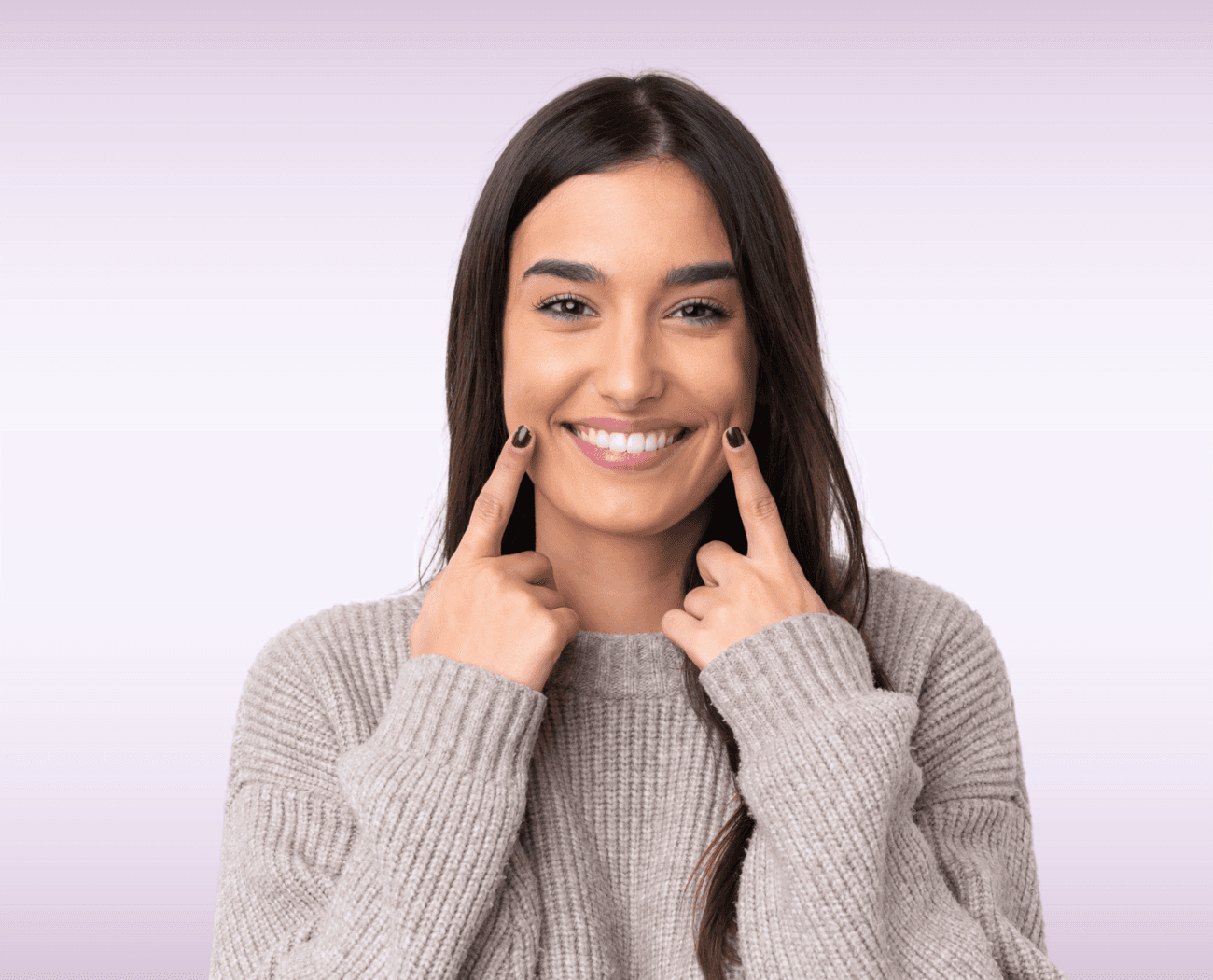 Woman smiling and pointing to her healthy mouth